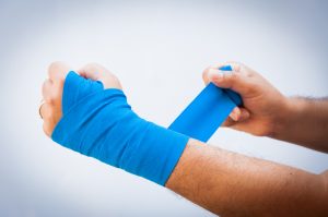 an injury, man bandaging his arm